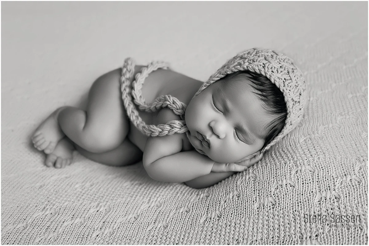 Newborn baby curled up and sleeping during her newborn photo session